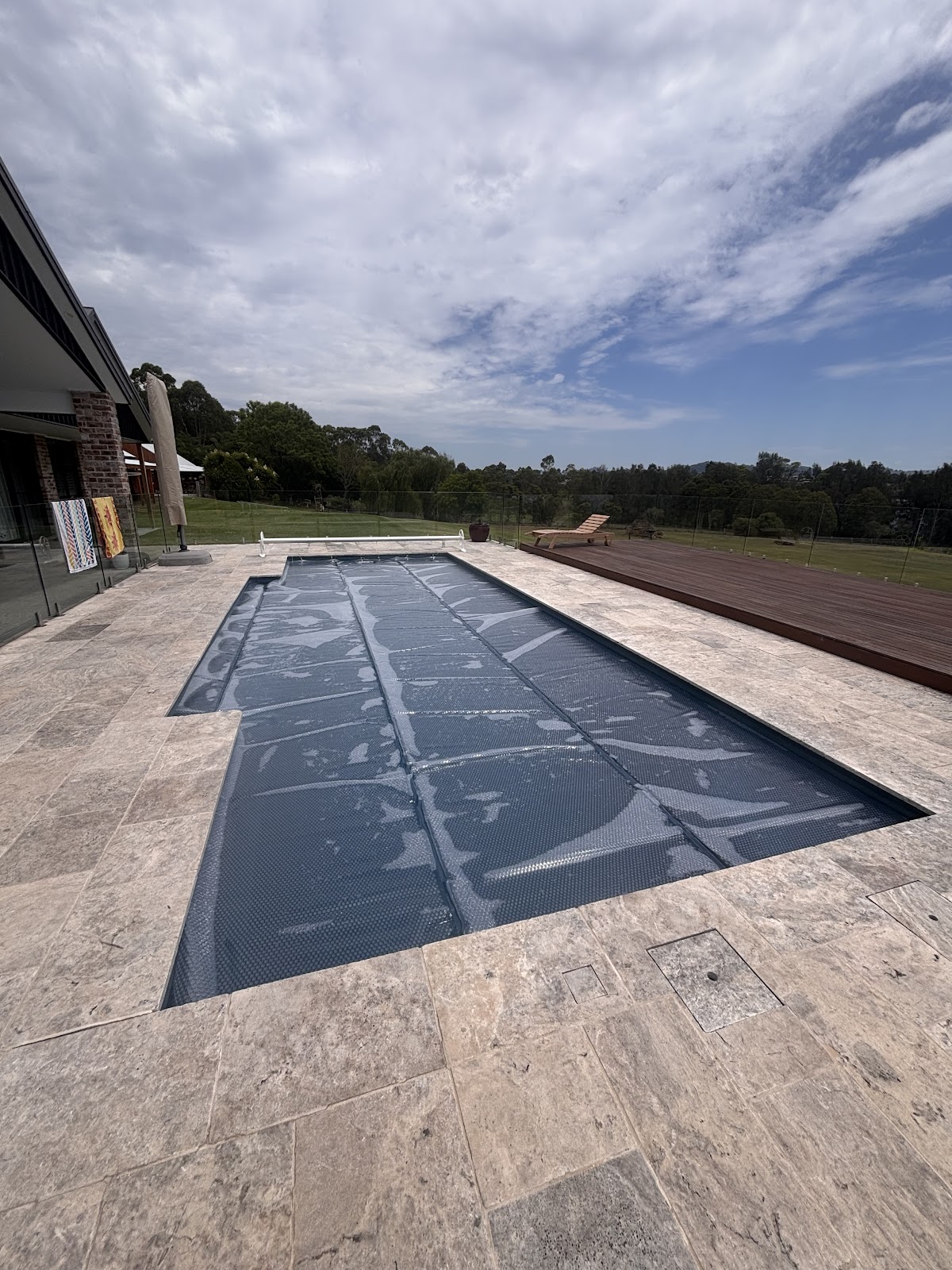 Rectangular pool with a solar cover on stone paving
