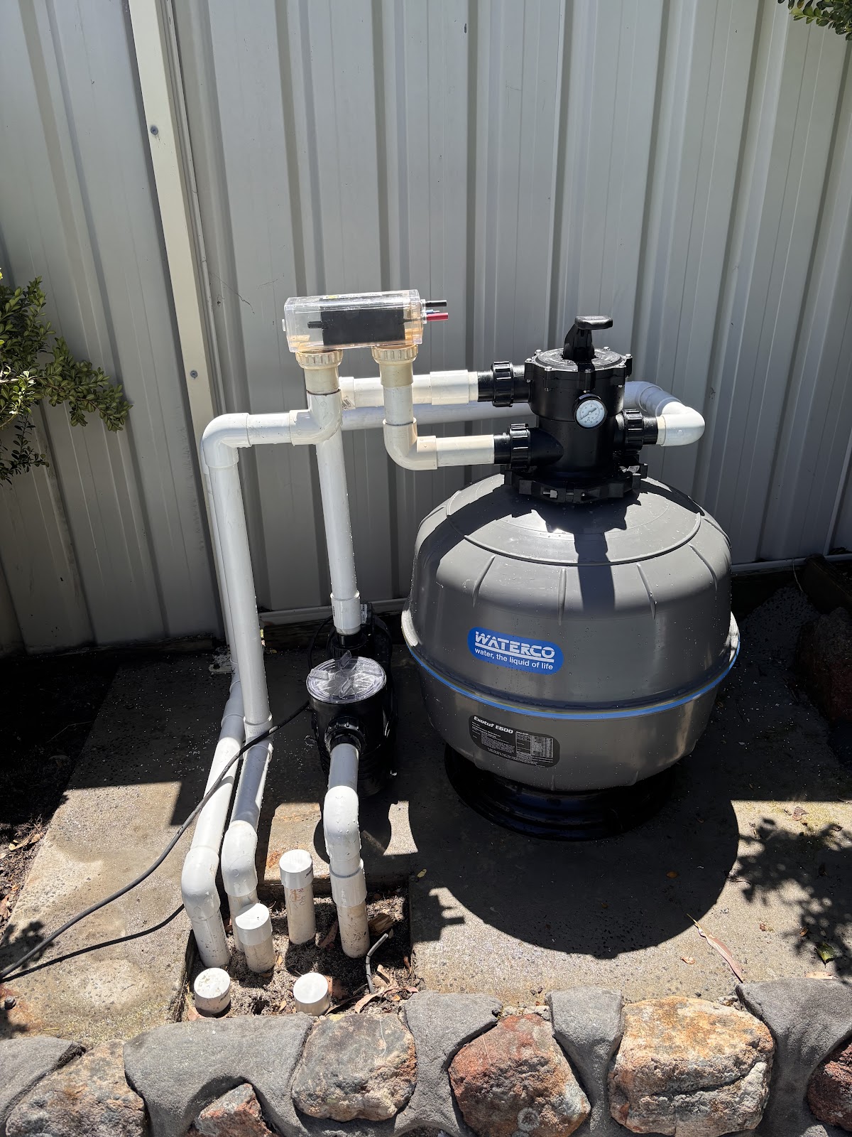 A new sand filter and pipework set up beside a shed wall